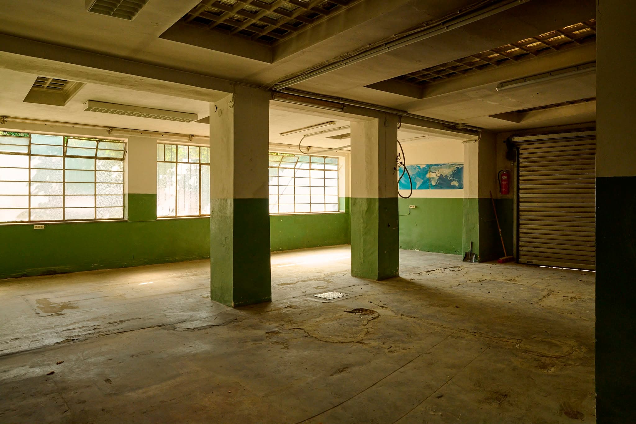 Leerstehende Industriehalle mit grün-weiß gestrichenen Wänden, großen Sprossenfenstern und Betonsäulen in den Rosenhöfen – Raum für künftige Ateliers